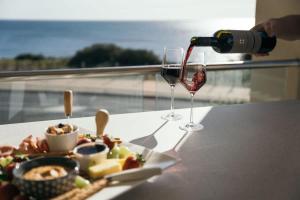 una persona sirviendo una copa de vino junto a un plato de comida en Dolce Vita Esplanade NobleBNB, en Port Willunga