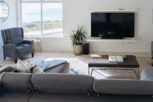 Una sala de estar con un sofá y un televisor. en Dolce Vita Esplanade NobleBNB, en Port Willunga
