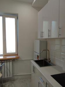 a white kitchen with a sink and a window at Ботанічний Сад in Kharkiv +2 photos