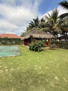a small hut with a grass roof on a yard at Casa Vacacional Valles de Olon in Santa Elena