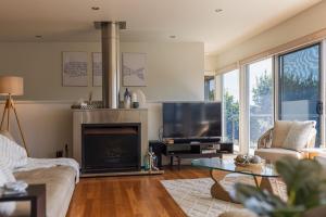 a living room with a fireplace and a flat screen tv at Morze Beachfront, Currarong in Currarong