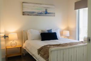 a bedroom with a bed with two lamps and a painting on the wall at Morze Beachfront, Currarong in Currarong
