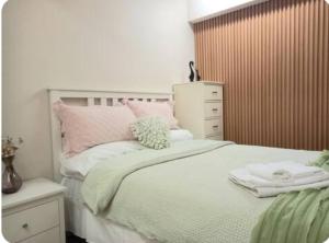 ein Schlafzimmer mit einem weißen Bett mit rosa Kissen in der Unterkunft 3mins walk to shopping centre city bus airport train station in Brisbane