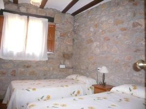 2 camas en una habitación con una pared de piedra en Casa Yayo en Puebla de Benifasar