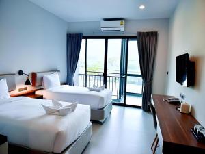 a hotel room with two beds and a balcony at @Sleep in Nakhon Pathom