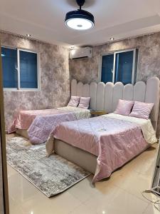 two beds in a room with pink sheets at Modern villa with pool and all comforts in Mendoza +18 photos