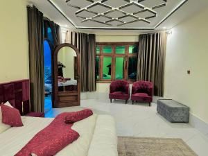 a bedroom with a bed and two purple chairs at Al Yaseen Continental Kalam in Kalām +26 photos
