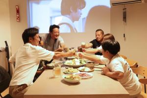 a group of people sitting around a table eating food at Ocean Living LA FUKU 和歌浦 一棟貸し 愛犬と泊まれる海辺の宿 in Wakayama