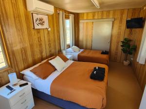 deux lits dans une chambre aux murs en bois dans l'établissement Birdsville Tourist Park, à Birdsville