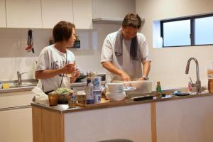 two chefs standing in a kitchen preparing food at Ocean Living LA FUKU 和歌浦 一棟貸し 愛犬と泊まれる海辺の宿 in Wakayama