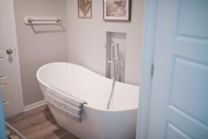 a white bath tub in a bathroom with a door at Charming and Private Birch Cottage in Idaho Falls +24 photos