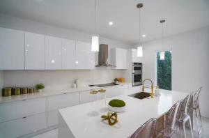 a white kitchen with a large white counter top at New 5BR Villa Beach Walk Jacuzzi Retreat in Pompano Beach +17 photos