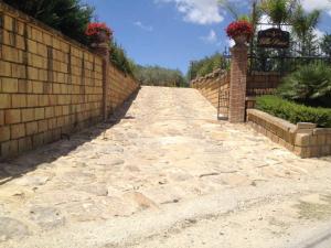 a stone road with a fence and flowers on it at Villa Russo in Caltanissetta