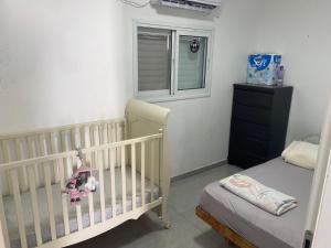 a baby room with a crib and a window at פנטהאוז in Petaẖ Tiqwa