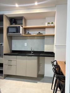 a kitchen with a sink and a microwave at Flat Moderno a 100m da Praia do Bessa in João Pessoa