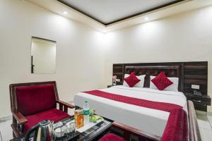 a bedroom with a bed and a red chair at Hotel Grand Lowsan Airport in New Delhi
