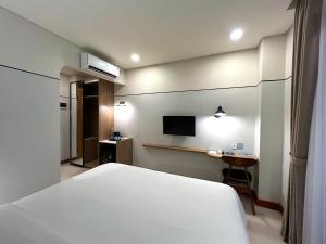 a bedroom with a white bed and a desk at Liberta Malioboro North in Yogyakarta