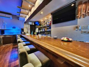 a bar with chairs and a television on the wall at ゲストハウスＰｉｋｏ in Shingu