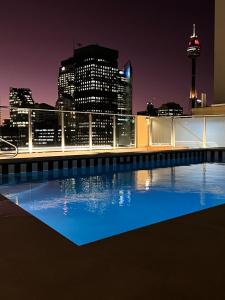a view of a city skyline at night from a rooftop pool at Paxsafe Sydney Hyde Park Private Apartments in Sydney