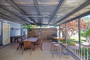 un patio con tavolo, sedie e griglia di Mermaid Cottage a Hawks Nest