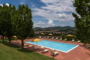 a swimming pool with chairs and umbrellas in a yard at Podere Torricella in Montagnana Val di Pesa
