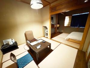 a room with a chair and a table and a bed at ハニー in Yokoshima