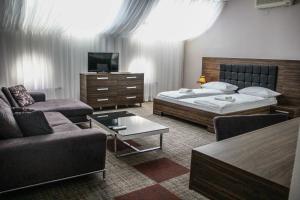 a bedroom with a bed and a couch and a tv at Hotel Story in Sarajevo