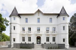 une grande maison blanche avec une tourelle dans l'établissement Château Autignac, à Autignac