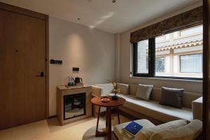 een woonkamer met een bank en een raam bij Huazhu Luxurious Mountain Courtyard Private Hot Spring Resort in Longmen