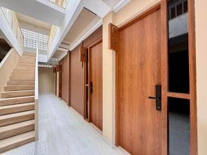 - un couloir avec une porte en bois et des escaliers dans l'établissement CIKOMI KOSTEL Syariah By Hans Management, à Tanjungkarang