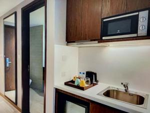 a kitchen with a sink and a microwave at MELLIA OCEANUS NHA TRANG BAY Five-Star Suites in Nha Trang