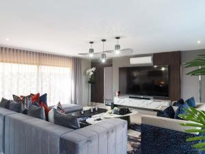 a living room with a large couch and a flat screen tv at Zimbali Hills 8, Zimbali Estate by Euphoric Leisure in Ballito