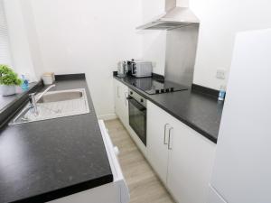 a kitchen with white cabinets and a black counter top at Holly House in Whitehaven +12 photos