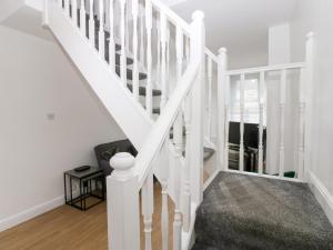 a white staircase in a home with white walls at Holly House in Whitehaven