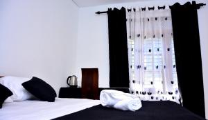a bedroom with a bed and a window with black curtains at Angel Haven Villa in Mirissa +3 photos