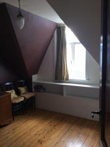 een zolderkamer met een raam en een houten vloer bij Villa Paul in Blankenberge