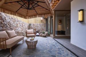 een woonkamer met een bank en een stenen muur bij Huazhu Luxurious Mountain Courtyard Private Hot Spring Resort in Longmen