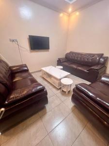 a living room with two leather couches and a tv at KIGALi GARDEN VILLA HOMES in Kigali