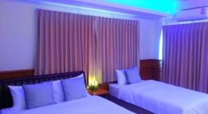 a hotel room with two beds and pink curtains at Seksub Place in Phra Nakhon Si Ayutthaya