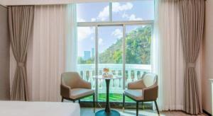 a bedroom with a bed and chairs and a large window at Zhuhai Dehan Hotel in Zhuhai