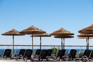 a group of chairs and umbrellas on the beach at Vila Alba Resort in Carvoeiro