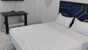 a white bed with a blue and yellow headboard and a table at Hotel O Eternity Stays in Rao