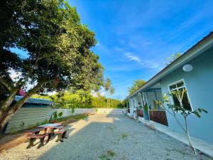 a group of picnic tables next to a building at Bloc Guesthouse in Pantai Cenang
