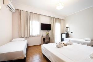 a hotel room with two beds and a television at Sonia Hotel & Suites in Kos Town