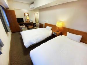 a hotel room with two beds and a desk at Hotel Route-Inn Fukaya Ekimae in Fukaya +20 photos
