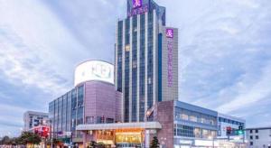 a tall building with a sign on top of it at Excemon Yuyao Hemudu Hotel in Ningbo