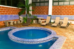 a swimming pool in a patio with chairs and a table at Hotel Puntarenas Beach in Puntarenas