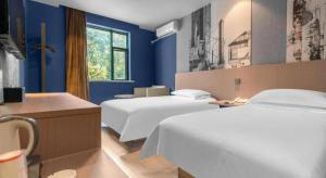 a hotel room with two beds and blue walls at Jinjiang Inn Wenzhou Shuangyu The Terminal in Wenzhou +188 photos