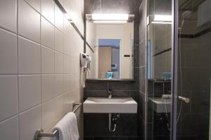 W łazience znajduje się umywalka i lustro. w obiekcie Bastion Hotel Barendrecht w mieście Barendrecht