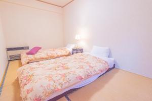 a bedroom with two beds and a lamp on a table at The Snowfront Apartment Nabe Sun -HAKUBA GORYU- in Hakuba